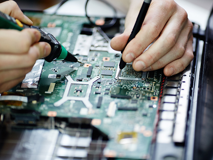 Close up of someone soldering electronics on a PCB